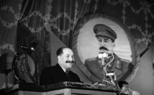 Каганович Лазарь Моисеевич, выступление на трибуне, на фоне портрета Сталина